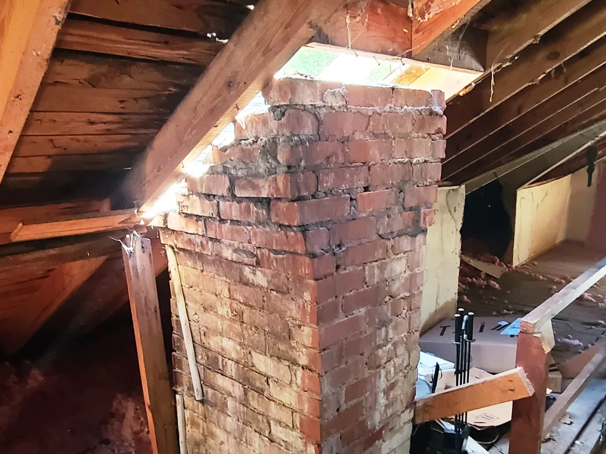 Brick chimney stack cut down inside an attic with the roof opened above it