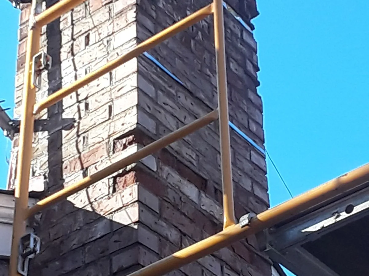 Brick chimney with scaffolding set against the roof for repair work