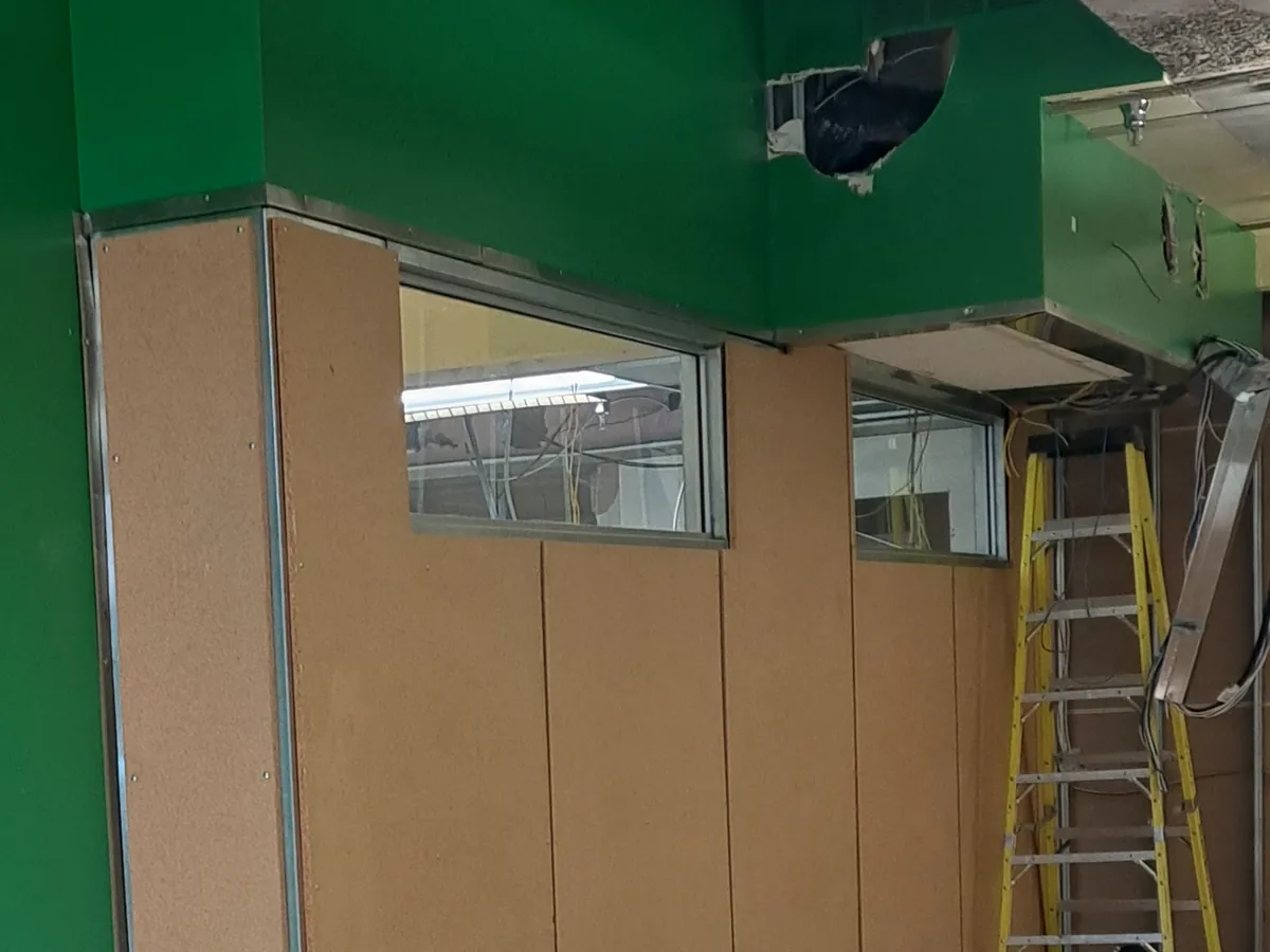Office corridor part-way through a strip-out with wall panels pulled and debris stacked