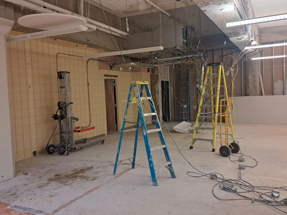 Commercial interior stripped back to the deck and conduit with ladders and stacked drywall