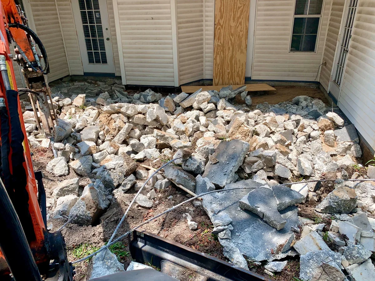 Broken concrete from a demolished patio piled beside the house ready to be hauled away
