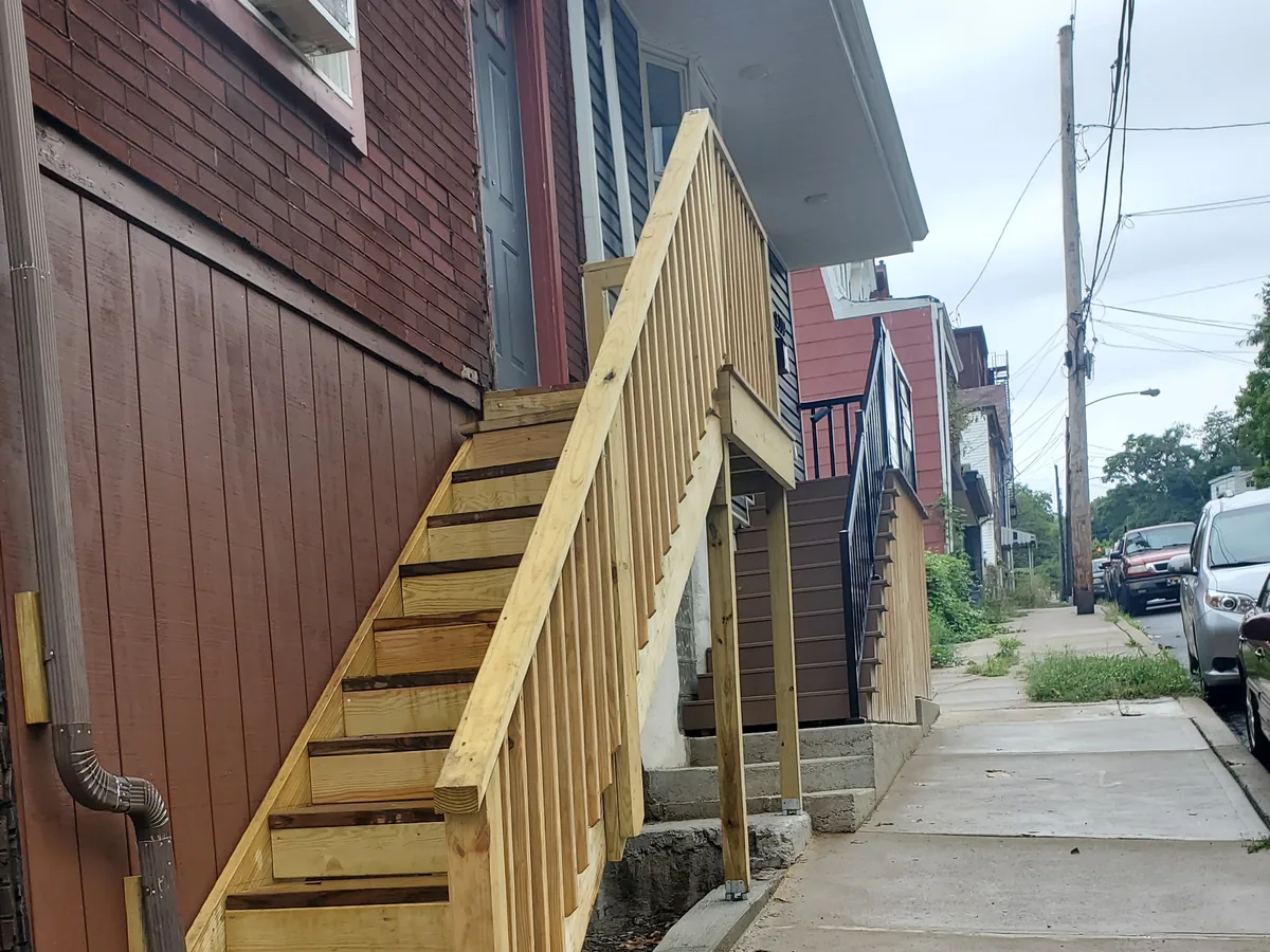 New wooden steps set on a fresh concrete pad beside a city sidewalk