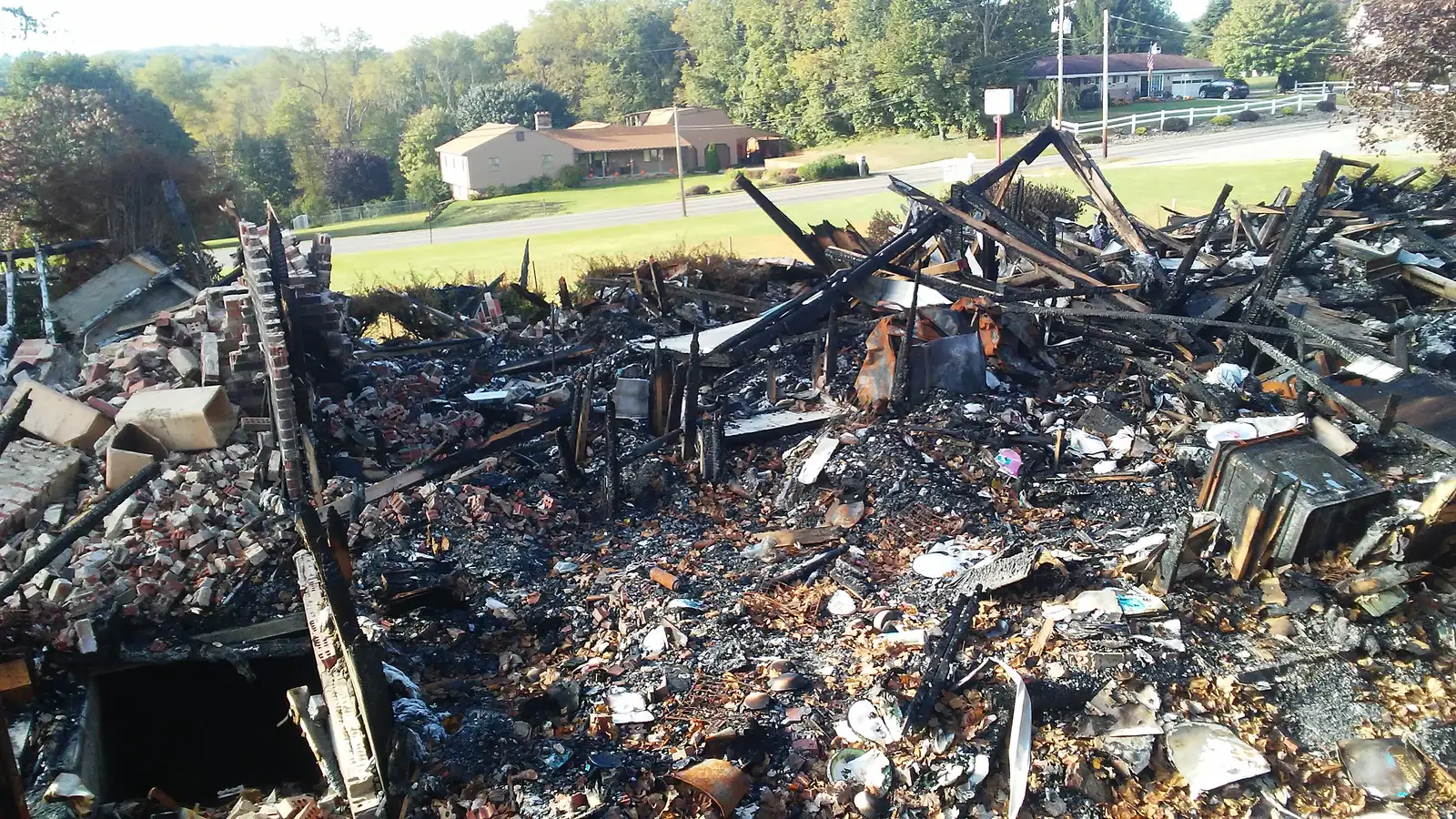 Charred debris from a fire-damaged structure piled on the lot