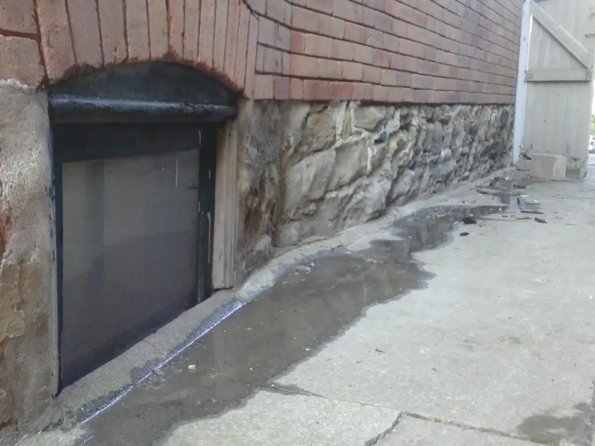 Stone foundation wall freshly parged around a basement window