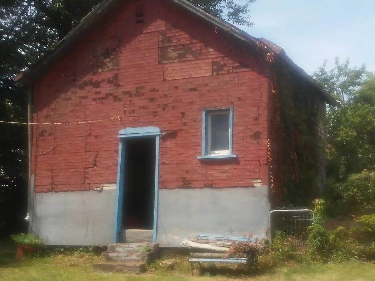 Small detached brick garage in a back yard before removal