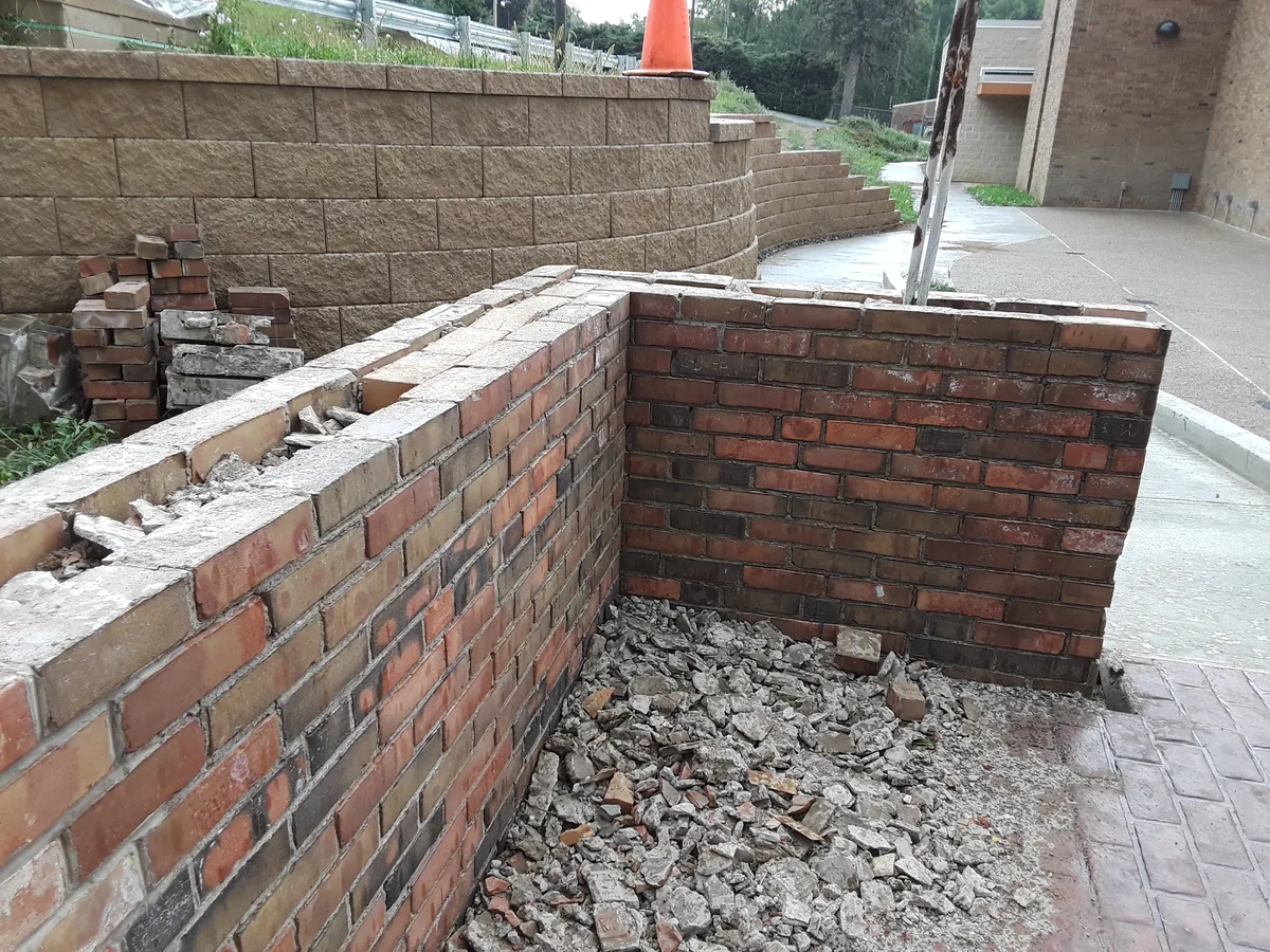 Brick garden wall being rebuilt above a block retaining wall