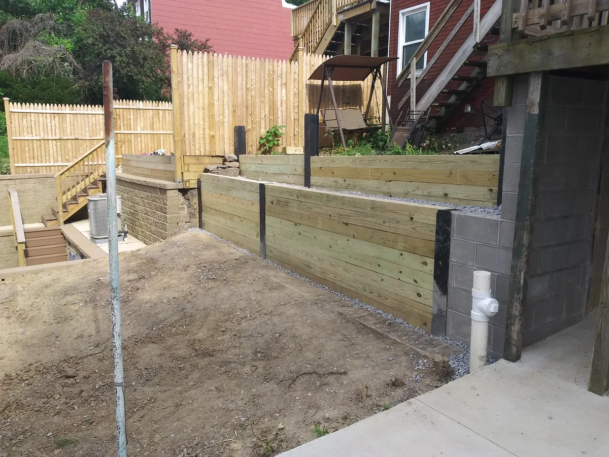 New timber retaining wall with built-in steps holding back a sloped yard
