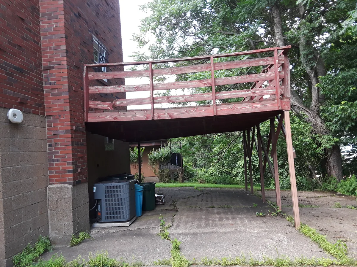 Second-storey wooden deck on the back of a brick building before it was taken down