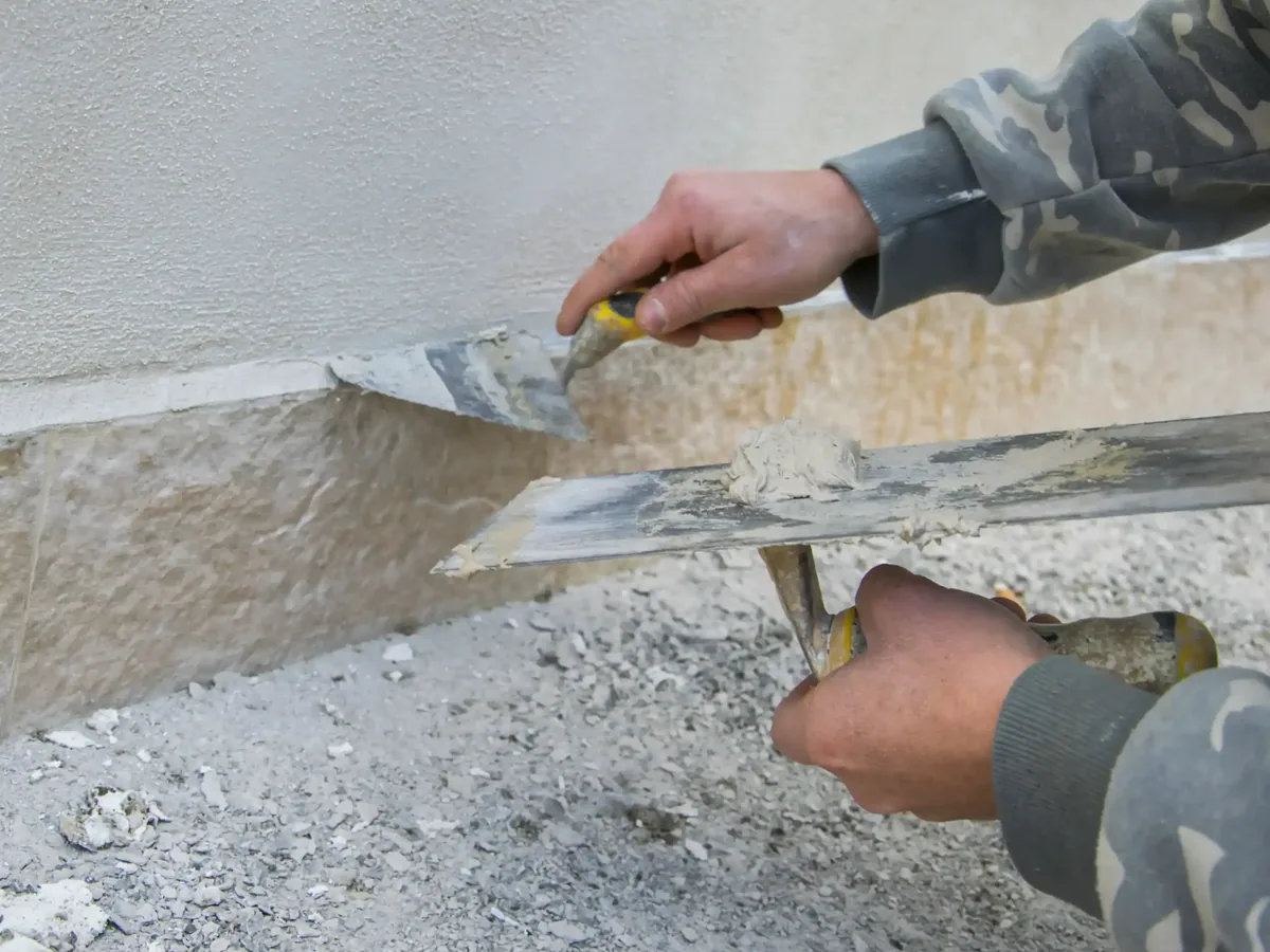 Patching a damaged stucco wall with a hawk and trowel